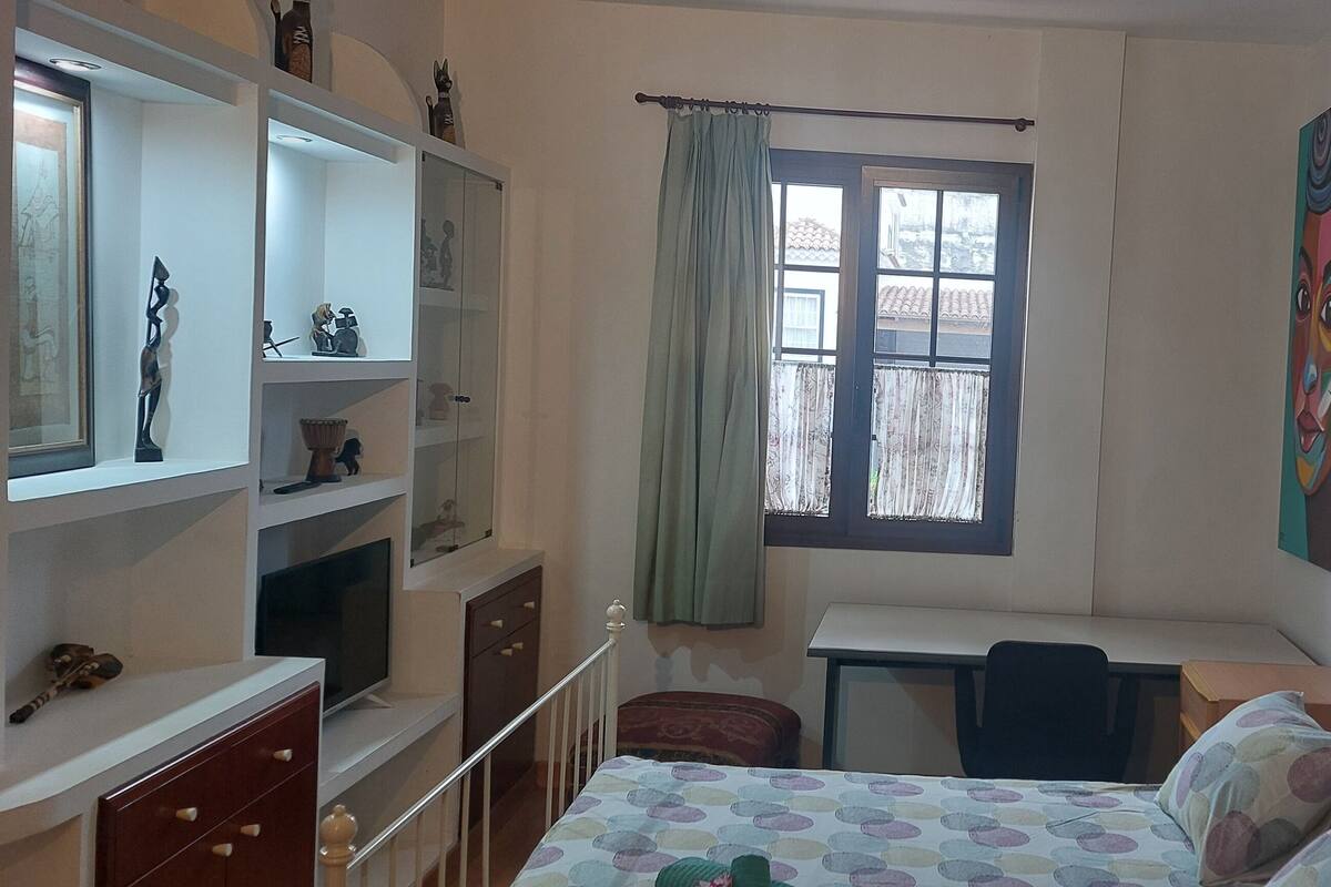 A bedroom with a bed, desk, chair, and shelves.