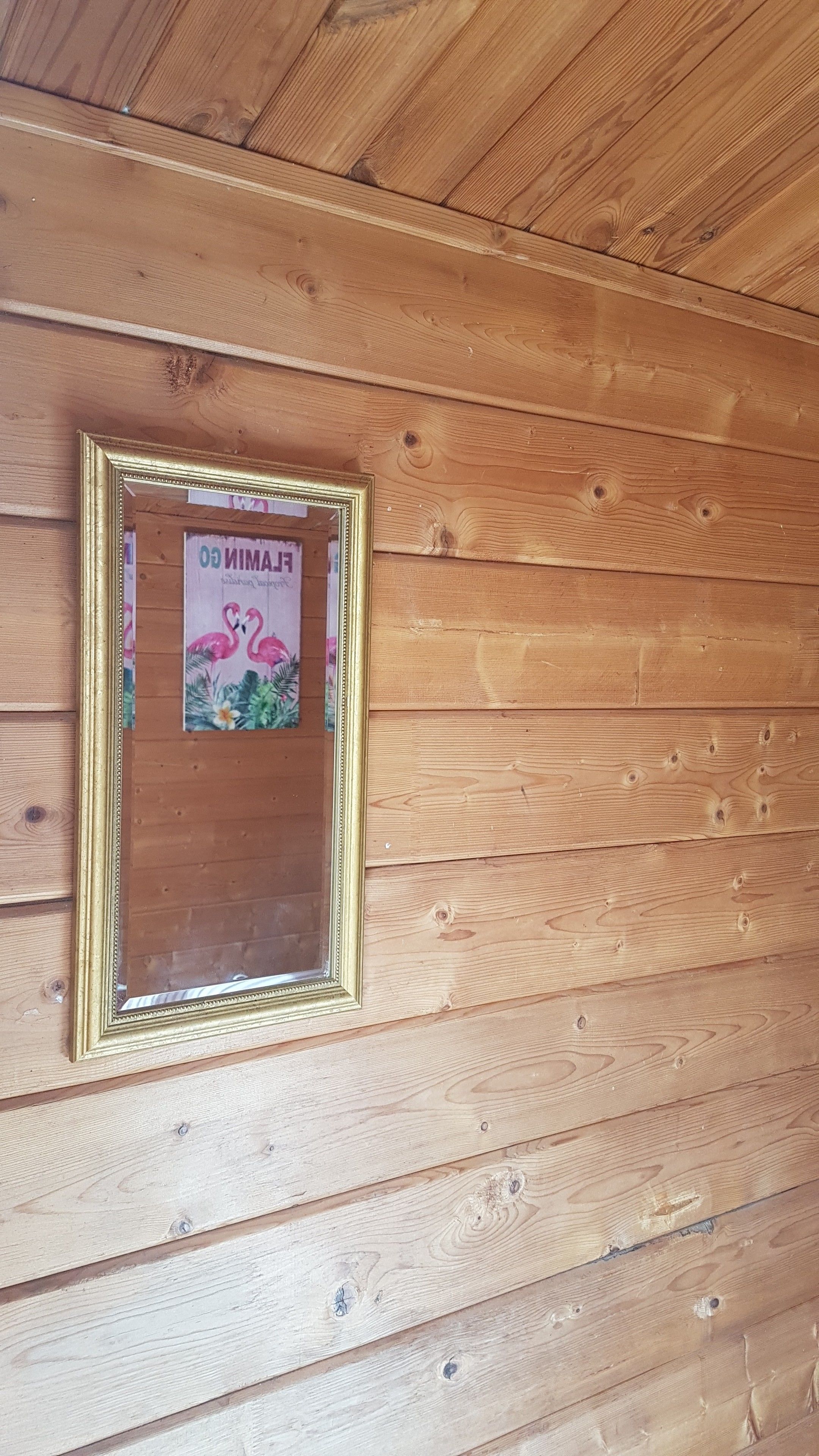 A framed picture with a flamingo design on a wooden wall.