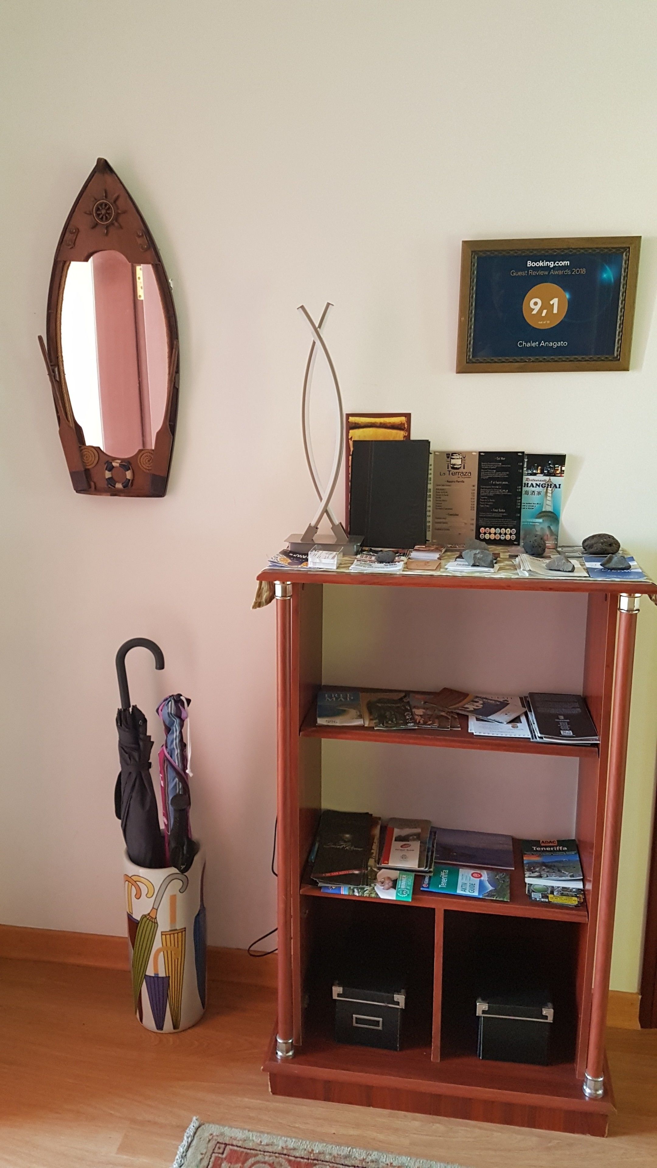 A wooden bookshelf with various items including books, a framed certificate, and a mirror.