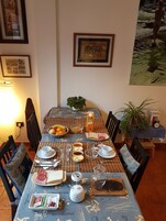 Una mesa de comedor lista con alimentos para el desayuno, una obra de arte enmarcada y una planta en maceta.