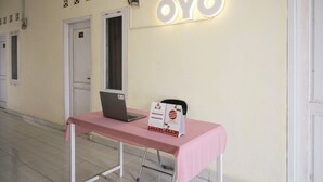 A reception area with a laptop on a table, a sign reading "OYO", and a door with the number 114. - OYO 654 Fabio Guest House Syariah (Bandar Lampung)