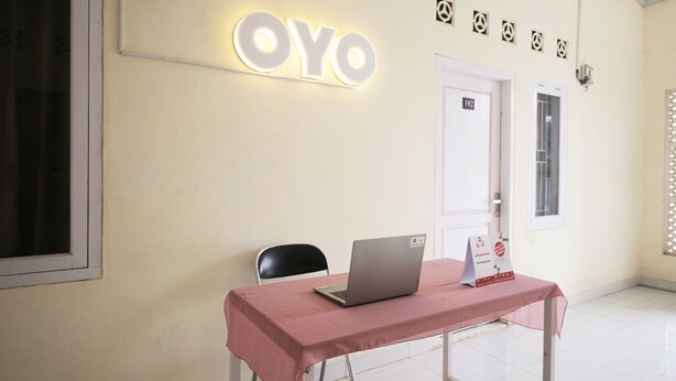 A room with a table, a chair, a laptop, and a sign that reads "OYO". - OYO 654 Fabio Guest House Syariah (Bandar Lampung)