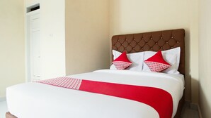 A neatly made bed with a red and white bedspread and two red pillows. - OYO 654 Fabio Guest House Syariah (Bandar Lampung)