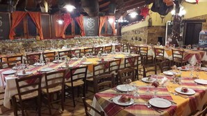 Un restaurante con varias mesas dispuestas para comer, que cuenta con una pared de piedra y vigas de madera.