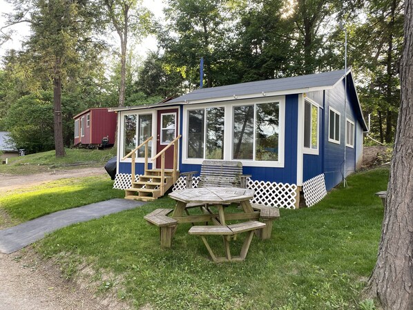 A small, blue cabin with a porch and a picnic table. - Waterfront, Rustic Cabin, Great Swimming, Own Dock, Raft (Tully)