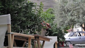 Un conjunto de mesa y sillas de madera al aire libre, con vista a una gran formación rocosa al fondo.