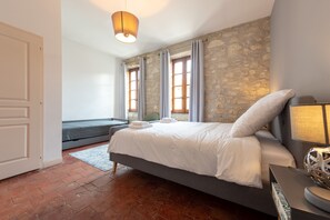 Un dormitorio con cama, mesita de noche, lámpara y pared de piedra.