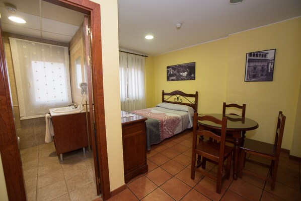 Quarto com cama, mesa de cabeceira e uma cadeira de madeira.