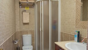 Ein Badezimmer mit Dusche, Toilette, Waschbecken und Handtuchhalter.