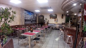 Ein Restaurant mit mehreren Tischen und Stühlen, einer Bar und einem Wandgemälde.