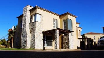 A two-story house with a stone facade, large windows, and a covered entryway.