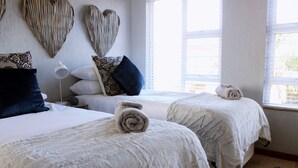 A hotel room with two beds, each with a rolled towel, white bedding, and decorative pillows. - Paradise At Rossmund Golf 5 Swakopmund (Swakopmund)