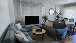 Un salon comprenant un canapé, une table basse, un téléviseur et un coin repas avec des chaises et une table.