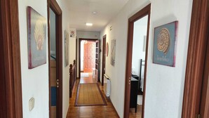 A hallway with wooden doors, a tiled floor, and framed artwork on the walls. - SABARIS, GARDEN AND PROXIMITY.  (Baiona)