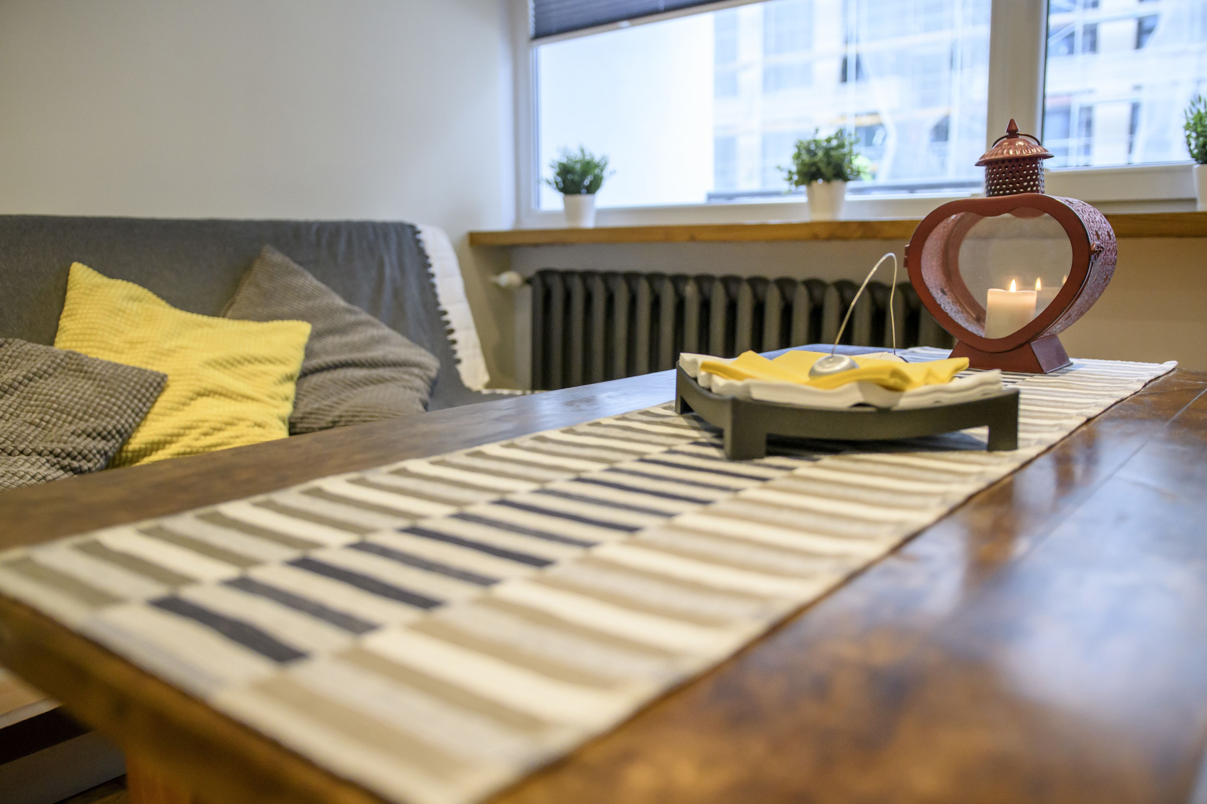 A living room with a piano keyboard rug, a table with a candle, and a heart-shaped lantern.