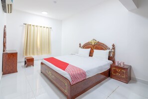 A neatly arranged bedroom with a wooden bed, a bedside table, a small stool, and a curtain.