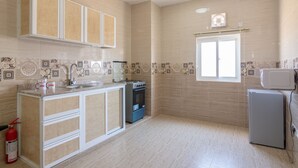 Eine Küche mit Herd, Backofen und Mikrowelle. Ein Fenster und ein Feuerlöscher sind vorhanden.