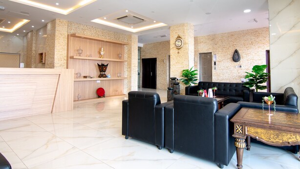 Eine moderne Lobby mit einer Rezeption, schwarzen Ledersofas, einem Marmortisch und einer großen Pflanze.