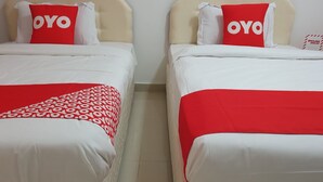Zwei zweibettige Betten mit passenden Kopfteilen und Fußstücken, jedes mit einem roten und weißen Kopfkissen mit dem Aufdruck "OYO".