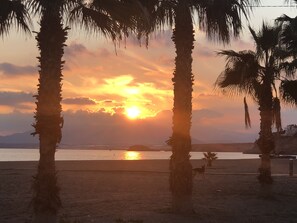 A beach scene with palm trees and a sunset over the water. - Beautifully presented Duplex House (Bolnuevo)