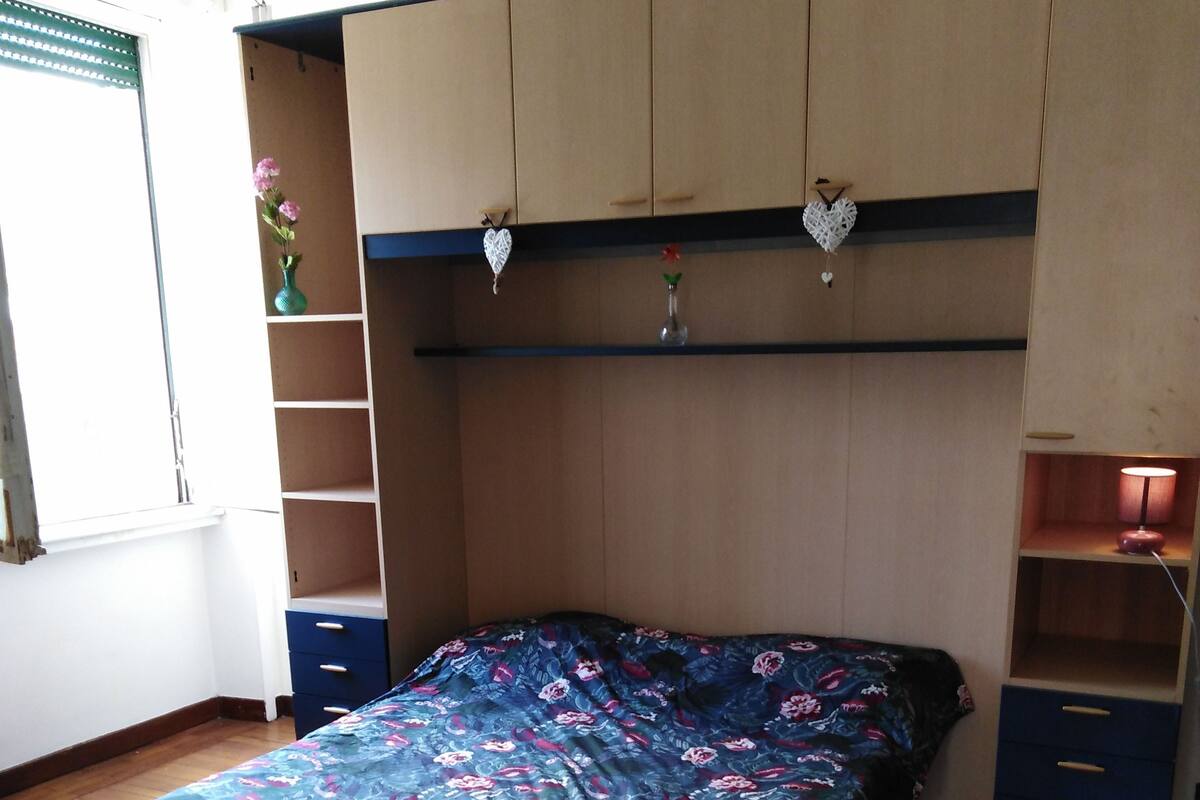 A bedroom with a bed, a desk, and a wardrobe.