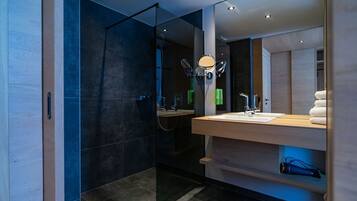 A modern bathroom with a glass shower enclosure, a wooden vanity with a mirror, and a towel rack.