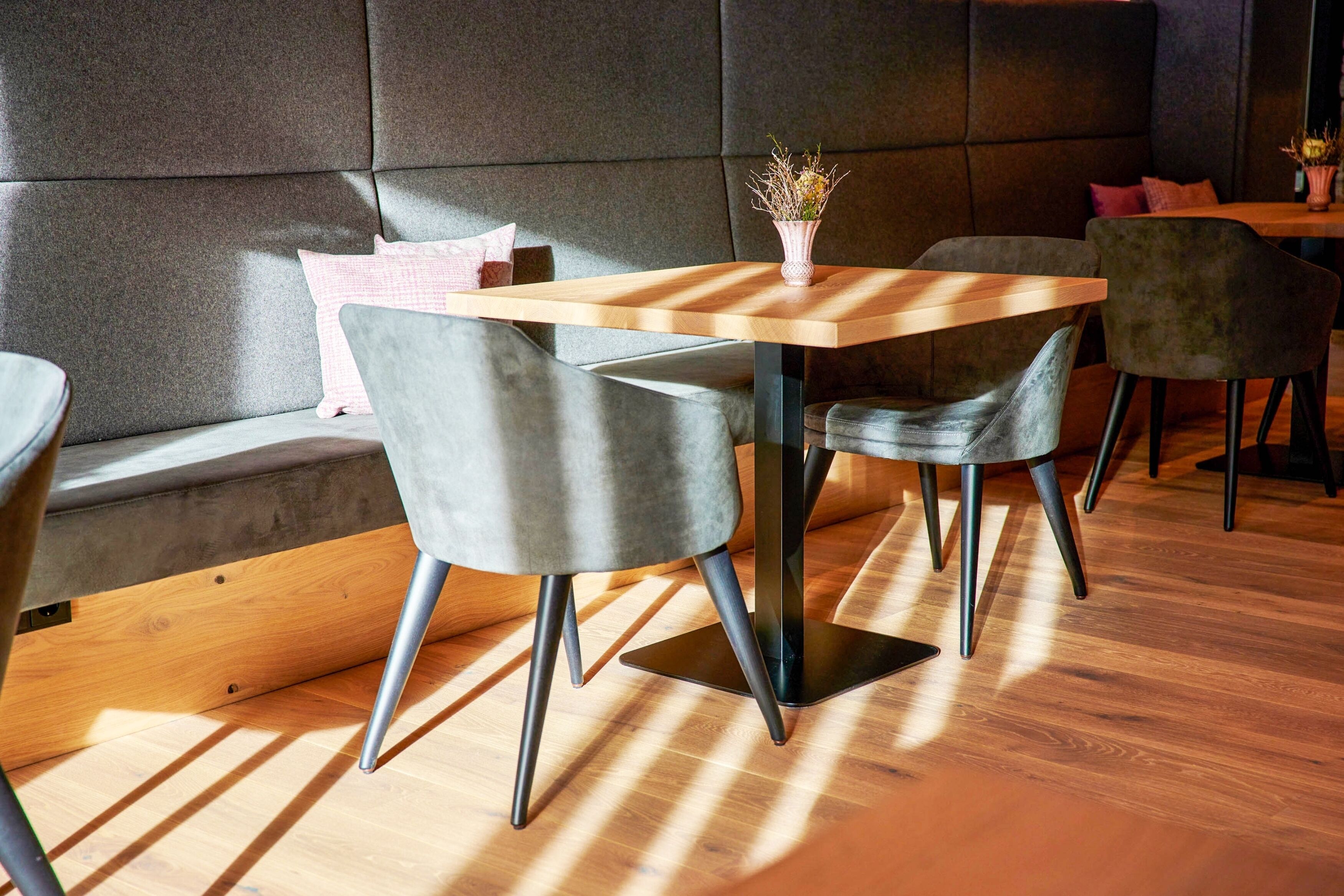 A modern dining area with a wooden table, grey upholstered chairs, and a cushioned bench.