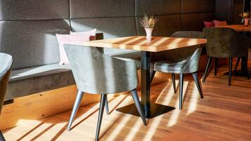 A modern dining area with a wooden table, grey upholstered chairs, and a cushioned bench.
