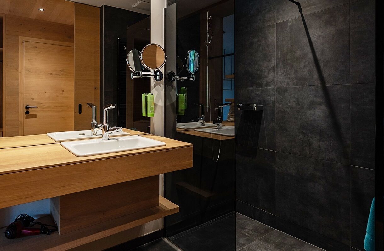 A modern bathroom with a wooden vanity, two sinks, and a large mirror.