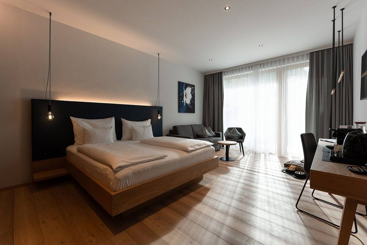 Ein modernes Hotelzimmer mit einem großen Bett, einem Schreibtisch und einem Stuhl.