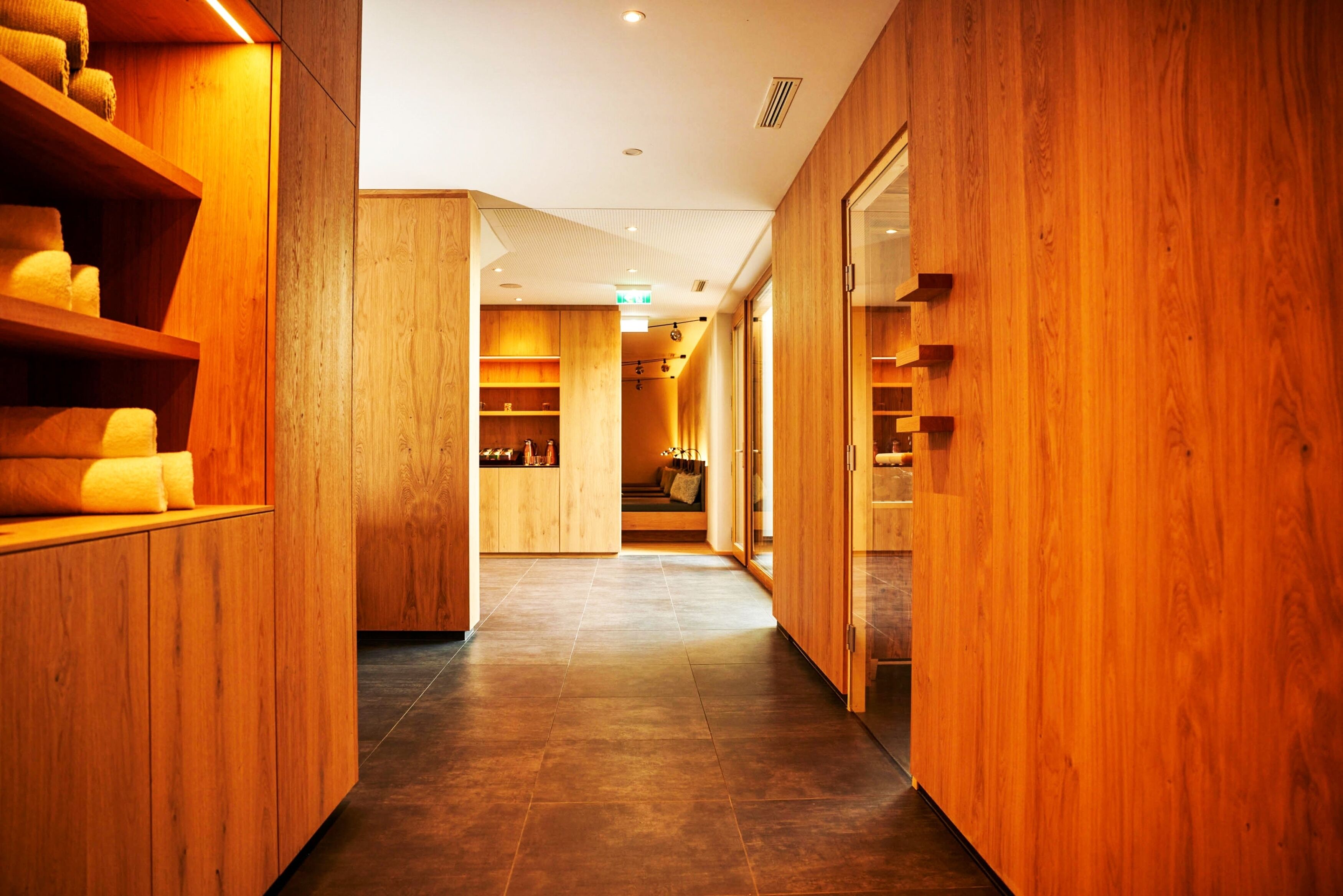 Un pasillo interior de madera con estantes y una zona de estar.