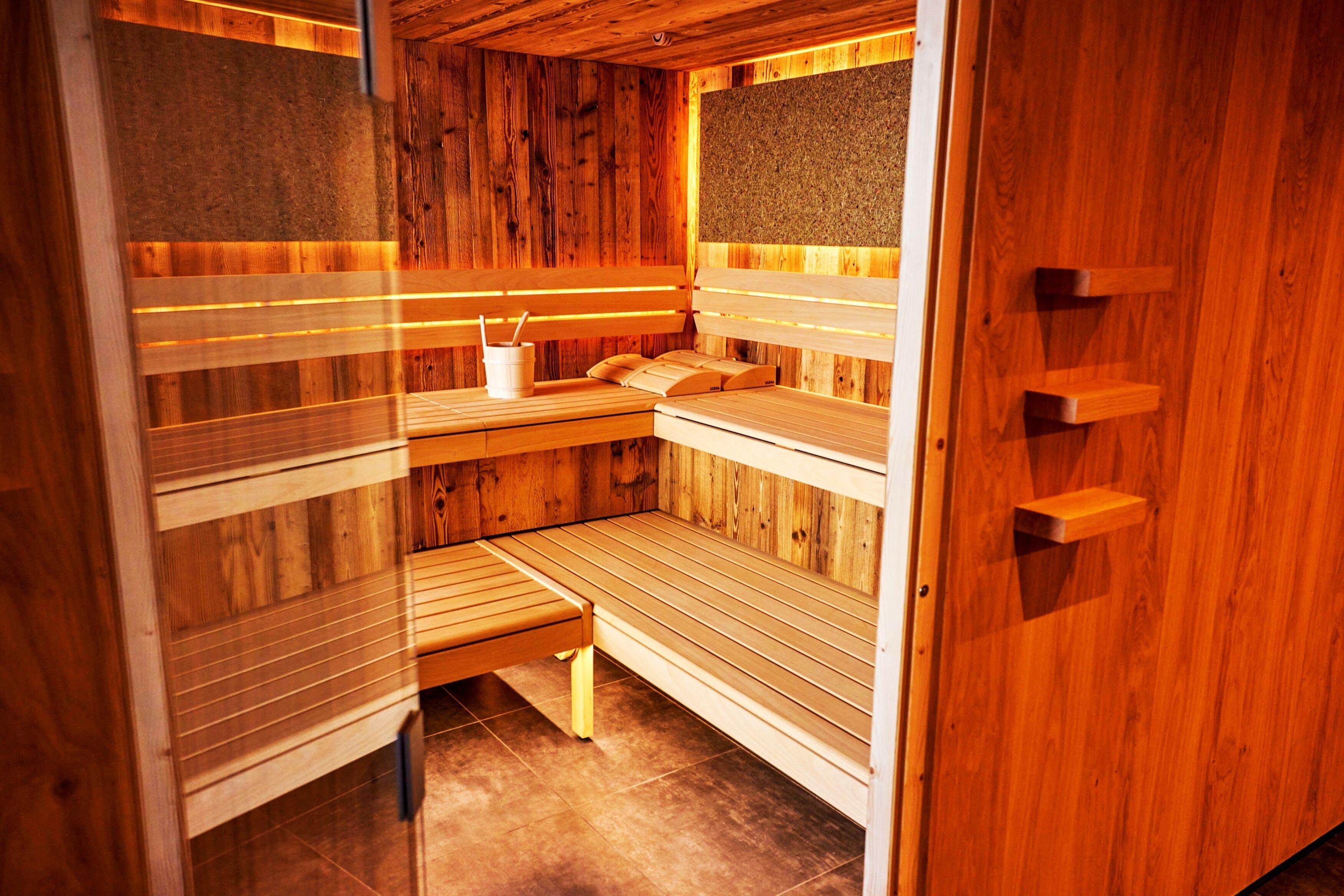 A sauna with wooden benches and a bench with a towel and cup.