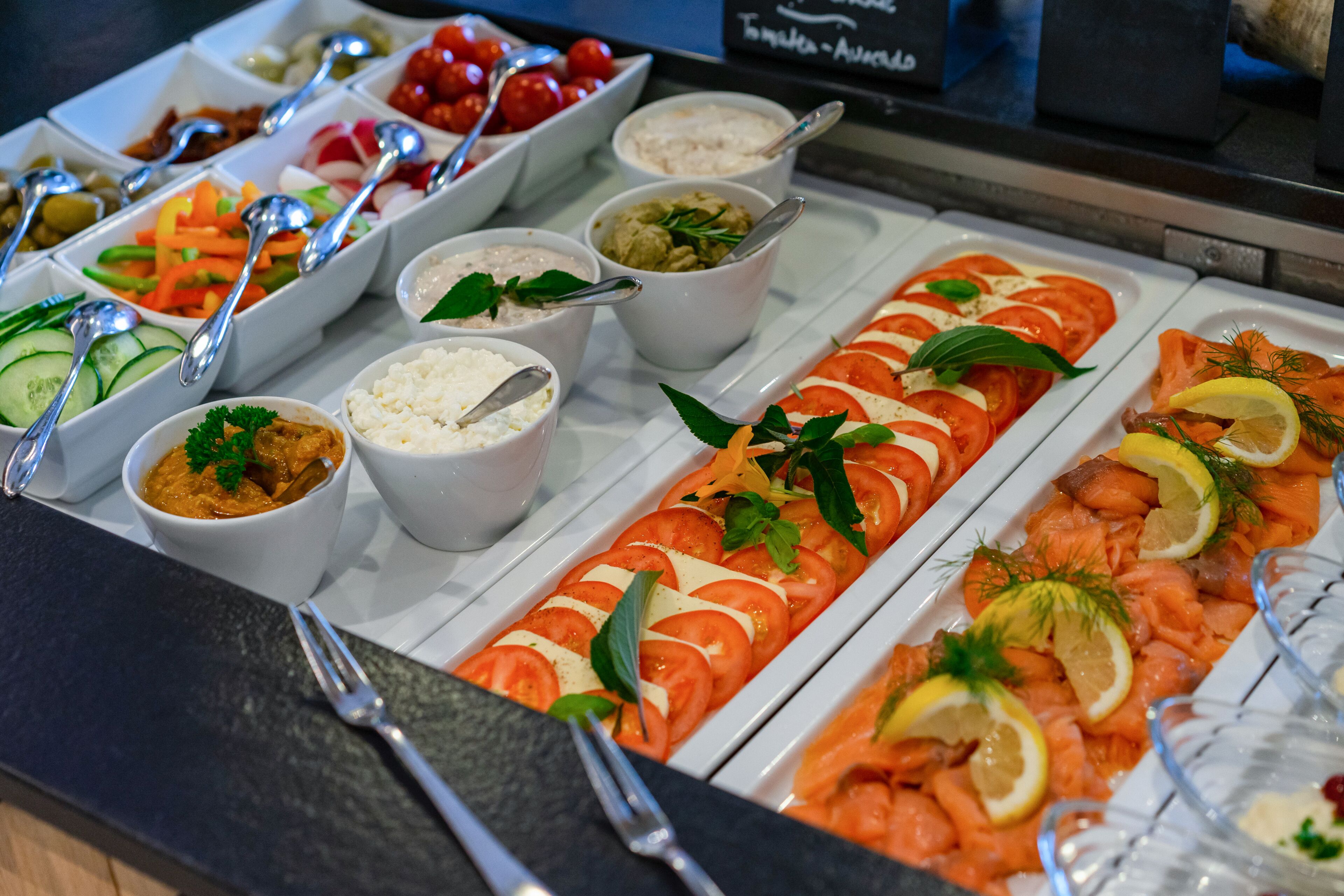 A buffet with various food options including salads, rice, and salmon.
