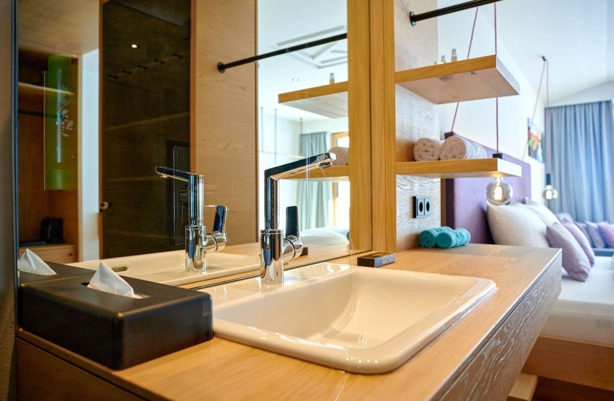 A modern bathroom with a large mirror, two sinks, and a wooden vanity.