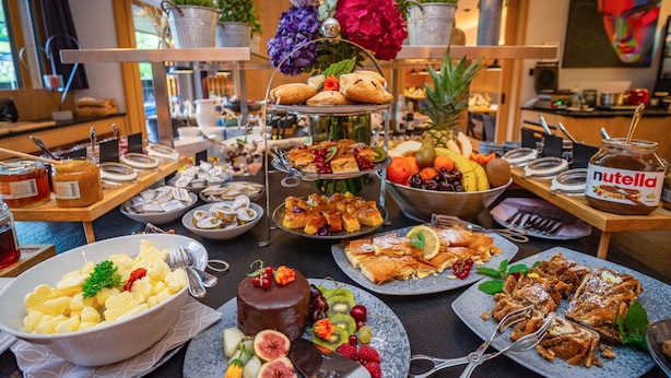 Ein Buffet mit verschiedenen Speisen, darunter Gebäck, Früchte und ein Schokoladenkuchen.