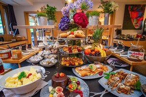 Un buffet proposant une variété de plats, notamment des pâtisseries, des fruits et un gâteau au chocolat.