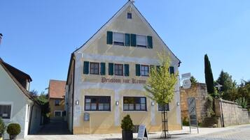 A building with a sign reading "Pension zur Krone" and a staircase leading to a door.