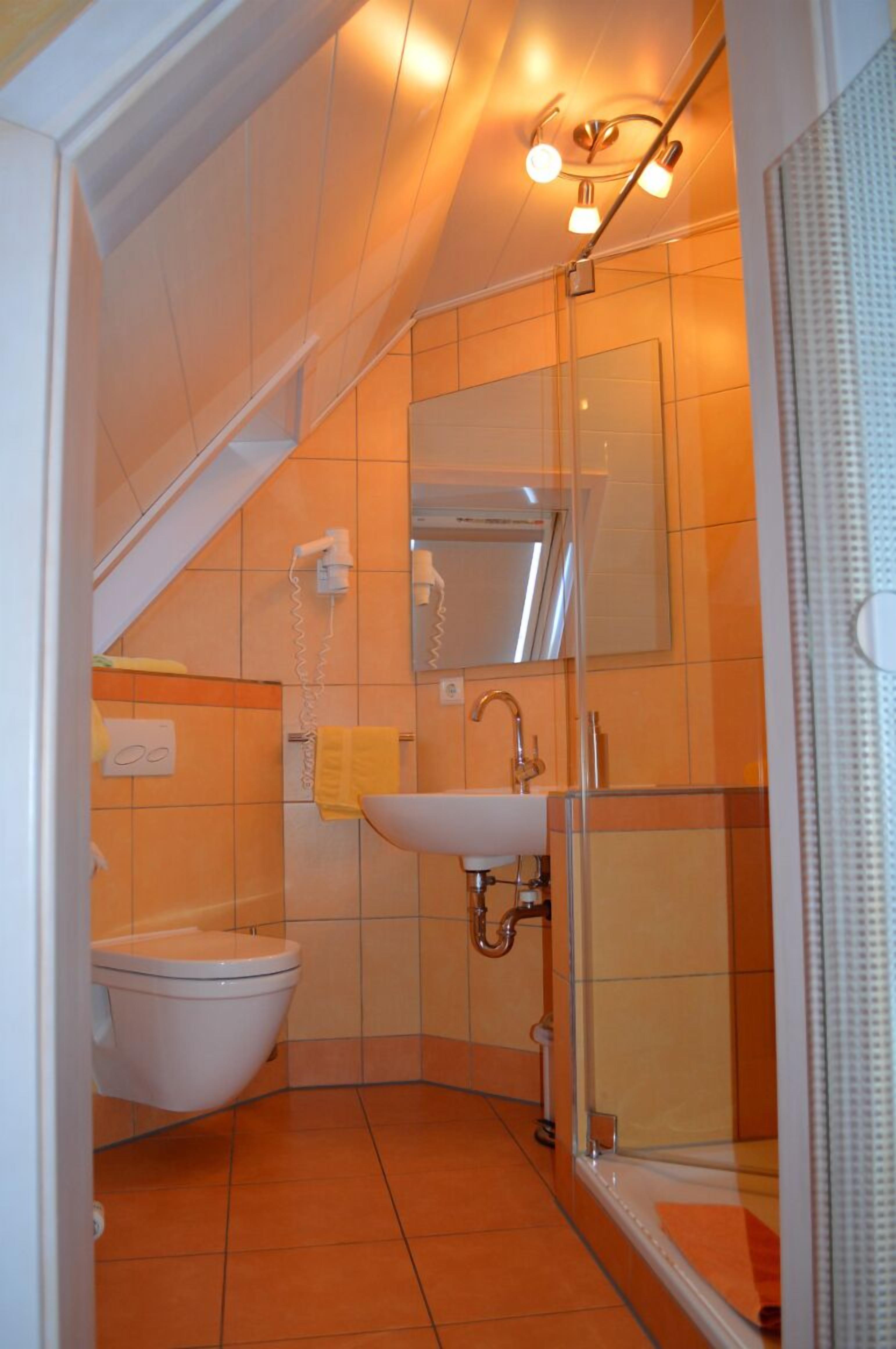 A compact bathroom with a toilet, sink, and shower.