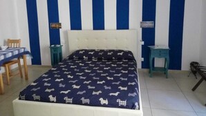 Un dormitorio con cama, una silla, una mesita y una mesita de noche.