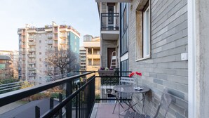 Un balcon avec une table et des chaises, une échelle et une rambarde.
