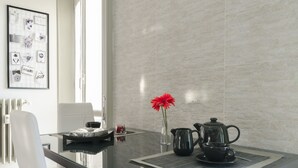 Une cuisine moderne avec une table en verre, une cafetière et un vase contenant une fleur rouge.