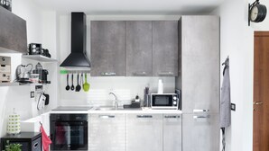 Une cuisine moderne avec des meubles gris, une hotte noire, un four à micro-ondes et un lave-vaisselle.