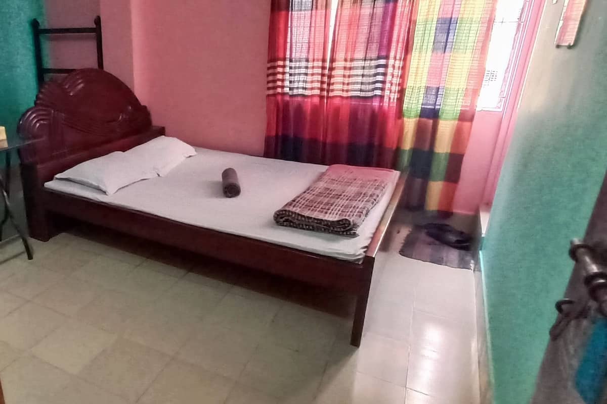 A small, compact room with a bed, a desk, and a chair.