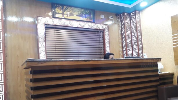 A reception desk with a patterned backdrop, a wooden slatted design, and a blue ceiling. - Hotel As Shams international (Dhaka)