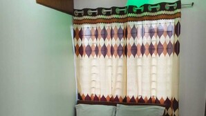 Una cama individual con una colcha estampada, almohadas blancas y un par de toallas.