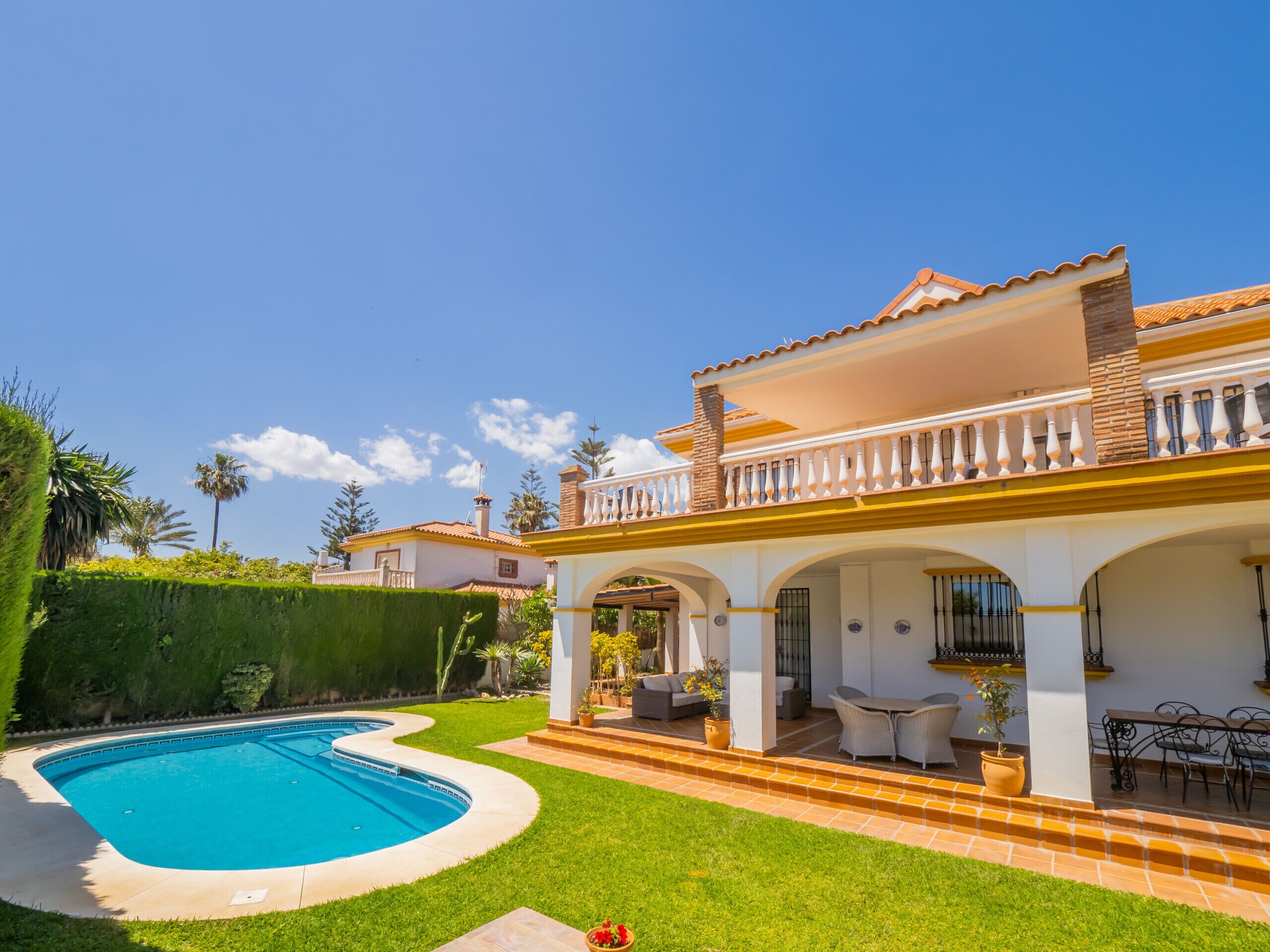 A house with a swimming pool, outdoor seating, and a well-maintained garden.