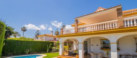 A house with a swimming pool, outdoor seating, and a well-maintained garden.