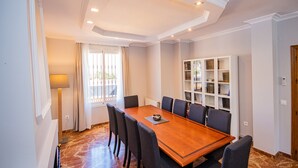 Une salle de conférence avec une table en bois, six chaises, une bibliothèque et une fenêtre avec des rideaux.