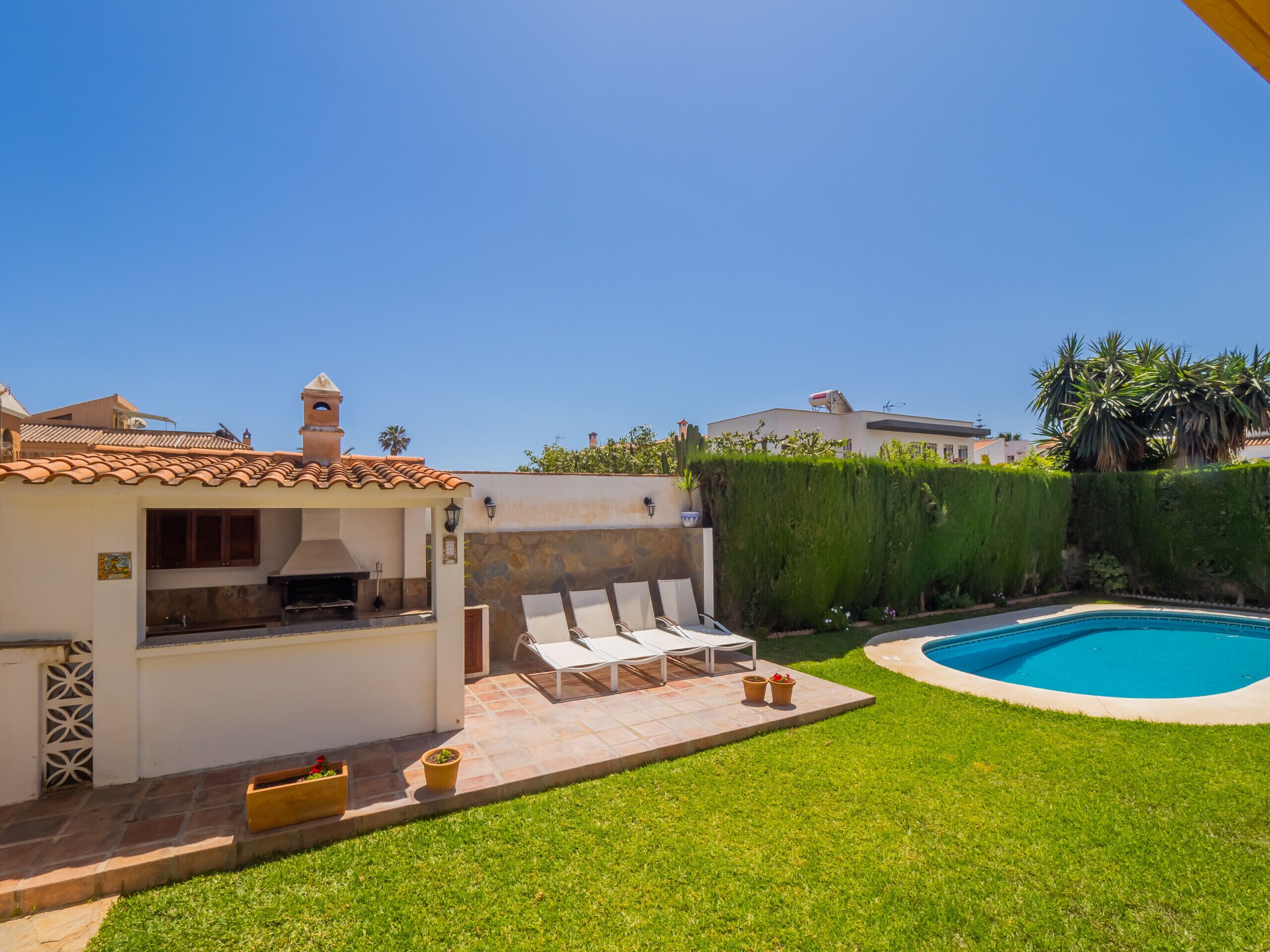 Ein Garten mit Pool, Grillplatz und einem gepflegten Rasen.