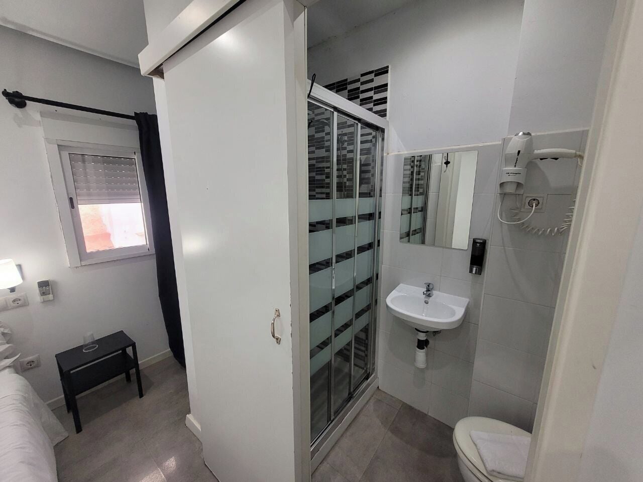 Casa de banho moderna com cabine de duche em vidro, lavatório branco e sanita.